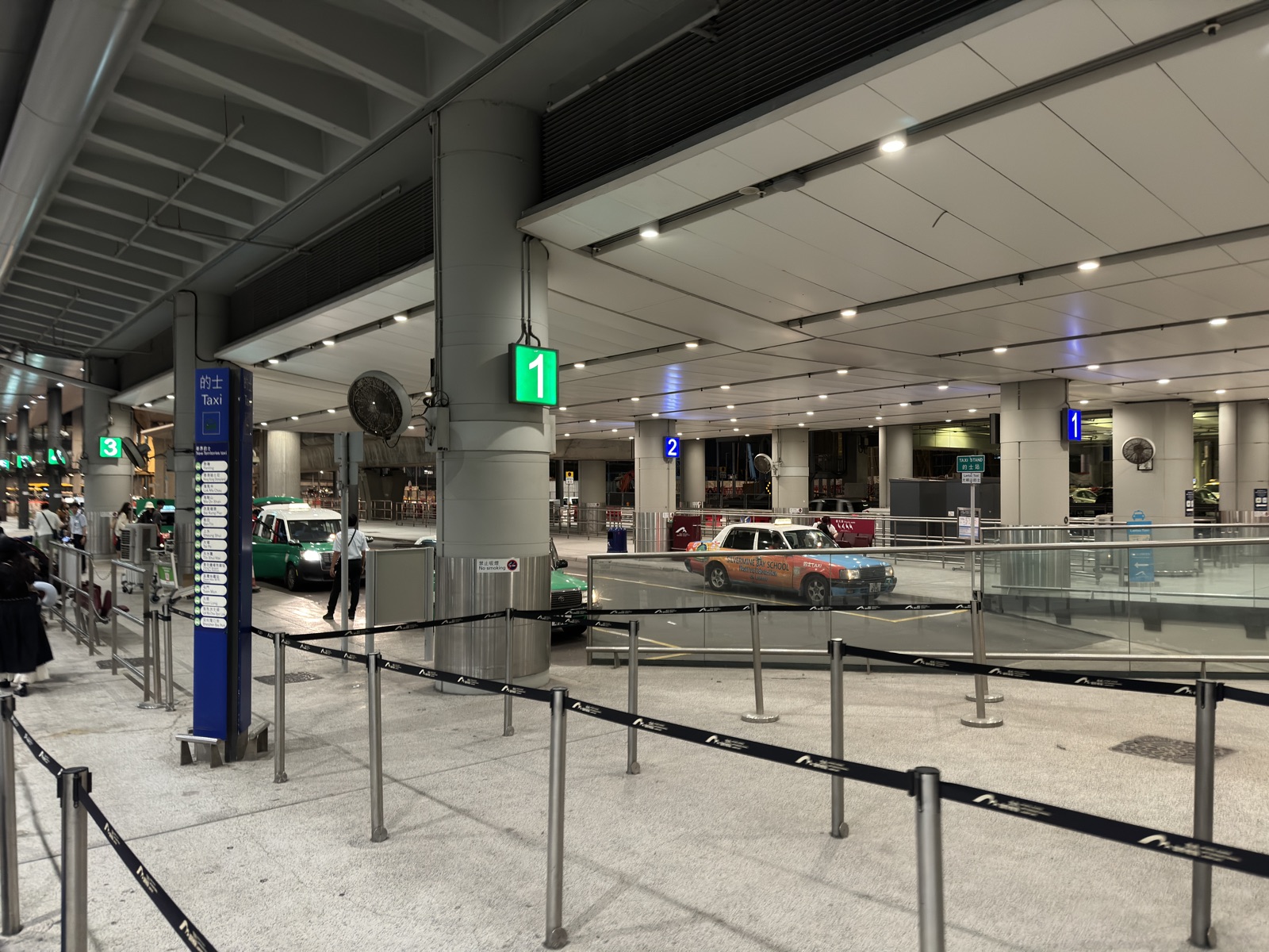 The airport taxi rank with colour-coded stands — red urban, green New Territories, blue Lantau.