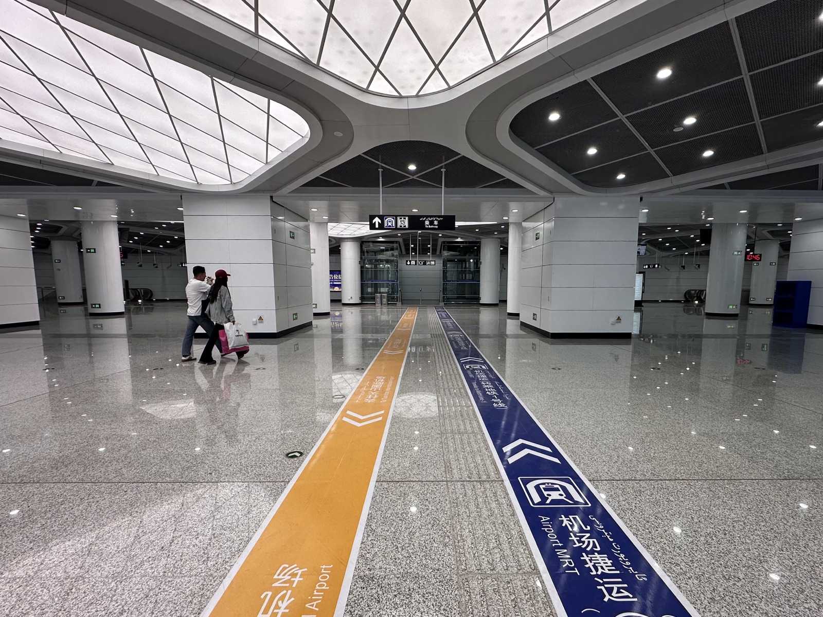 Ürümqi airport metro / Airport Express concourse with ticket machines and Line 1 wayfinding.