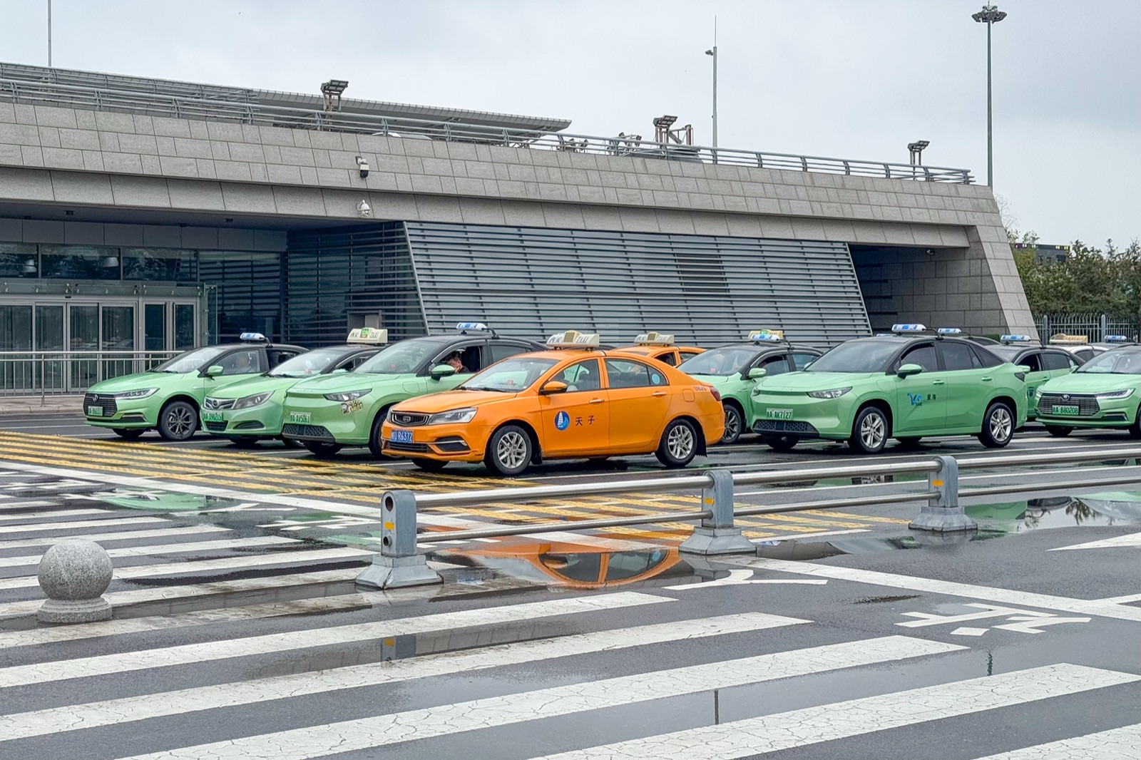 The official metered taxi rank outside Xi'an Xianyang Airport arrivals, taxis queued at the curb.